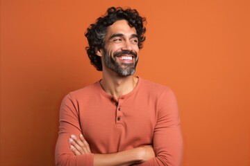 Obraz premium Handsome man with beard smiling and looking at the camera on orange background