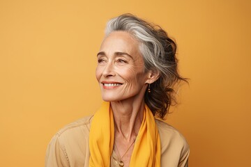 smiling senior woman in yellow scarf looking at camera isolated on yellow