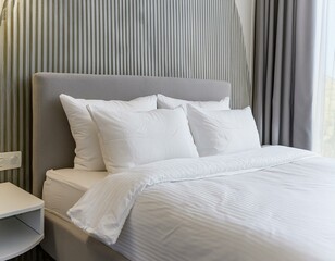 Close-up on minimalistic hotel bedding clean white pillows, duvet blankets, bedsheets neatly placed on a bed linen