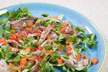 Plate of anchovies with cherry tomatoes and rocket.