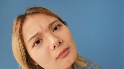 Close-up of young woman looking at camera as if in mirror isolated on blue background