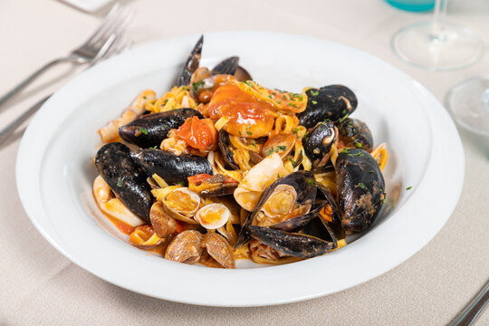 Tagliolini allo scoglio, homemade Italian pasta with mussels, clams, calamari, scampi, prawns and tomato. Seafood tagliolini