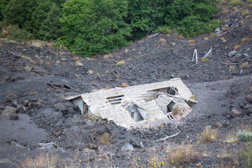 House covered with lava on the slopes of Mount Etna, Sicily, Italy. A previous eruption of the volcano covered the house with lava