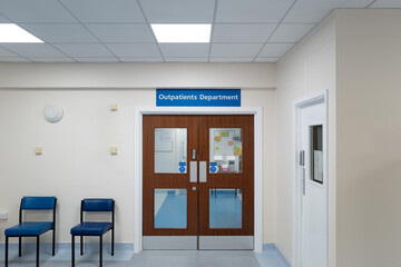 Typical NHS Out Patients waiting room seen in a hospital in England. Through the double doors are...