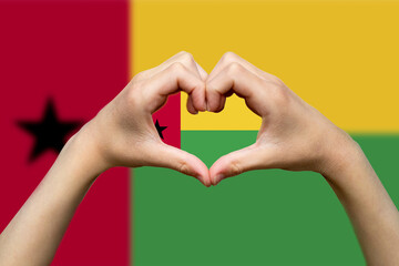 Guinea Bissau flag with two hands heart shape, hand heart love sign, support or donate to Guinea 