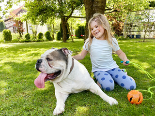 Cute little toddler girl playing with family dog in garden. Happy smiling child having fun with...
