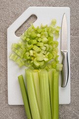Diced green celery stalks on stone white board top view.