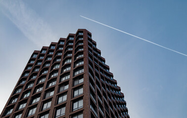 A trace of a passing plane over a modern multi-storey business class building.