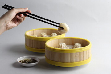 handmade steamed Shanghai Xiao long bao pork meat mini dumpling soup in bamboo basket on white...