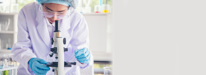 Banner Asian woman scientist hand write note research in medical lab look at science microscope....