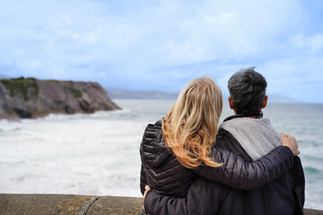 A rear view of a gay women couple hugging on a pier looking at the horizon. united family - Powered by Adobe