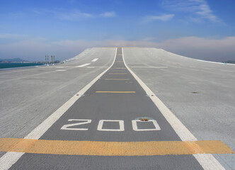 Tarmac runway track on deck of aircraft carrier with blue sky