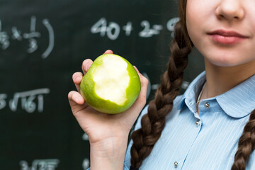 Sweet lesson: Girl with an apple - a symbol of health and education against the backdrop school...