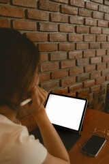 Back view of asian Thai woman using laptop, showing white blank screen, working as freelance in cafe alone.