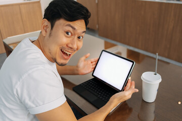 Asian man smiling, wow face, hand presenting and recommending some idea on white blank screen of laptop, great choice, working and sitting in cafe.