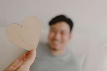 Photo of woman hand holding wooden blank empty space of heart design, showing love gesture and giving to asian man, lovely couple marriage, valentines concept.