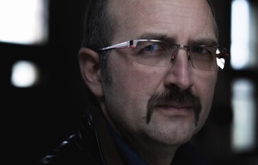 Portrait of a middle aged man with moustache and eyeglasses, being serious