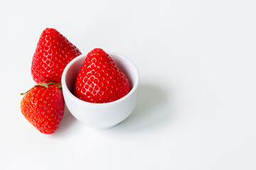 Fresh ripe strawberries in and beside a white bowl