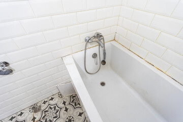 Interior of narrow restroom with wall hung toilet with white walls and checkered floor