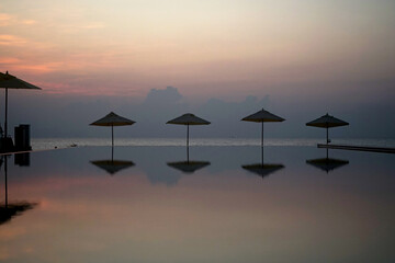 The beautiful before sunrise in the early morning with a beach umbrella by reflection on the...