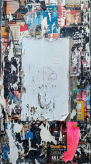 Fototapeta premium Blank white space on a chaotic, grunge wall filled with layers of torn, ripped, and colorful posters