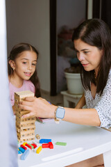 Fototapeta premium International Children Day. Beautiful Latino children playing with blocks on a white table. Playful, fun and thinking games. Happy children at home.
