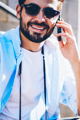 Cropped image of happy bearded young man in sunglasses talking with operator about favorable...