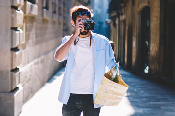 Young man tourist focusing and making photos on camera while strolling in narrow streets of old...
