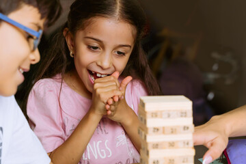 International Children Day. Pretty latin girl playing with colored blocks on a white table. Playful, creative and thinking games. Family day, happy children. - obrazy, fototapety, plakaty