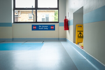 Recently cleaned hospital corridor floor seen together with a red fire extinguisher and Staff Only...