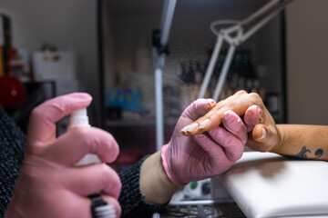 Manicurist applying fixative spray to enhance nail durability