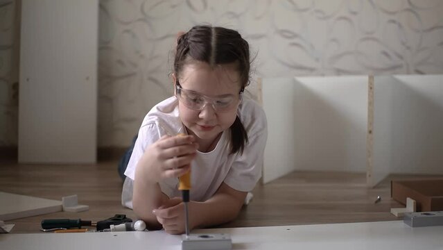 teenager collects furniture. assembles furniture. use a screwdriver. slow motion video. High-quality shooting in 4K format.