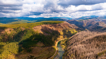 Spectacular view of mountains and river in the wilderness of Oregon State, the USA. Mt. Hood National Forest. Grey rainy clouds overcast the sky above the landscape. Top perspective.