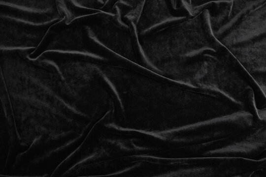 Texture of black velour fabric, top view. A noble dark shade with rich drape and a smooth texture with a beautiful matte sheen. background texture, pattern.