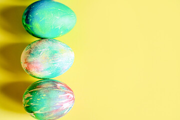 Easter brightly decorated pastel eggs in delicate blue, green, pink, yellow colors lie on a yellow background with space for text