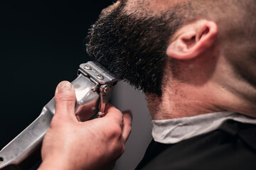 A man is getting his beard trimmed by a barber