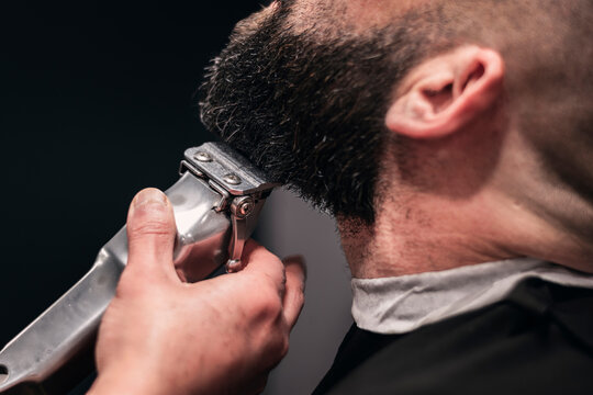 A man is getting his beard trimmed by a barber