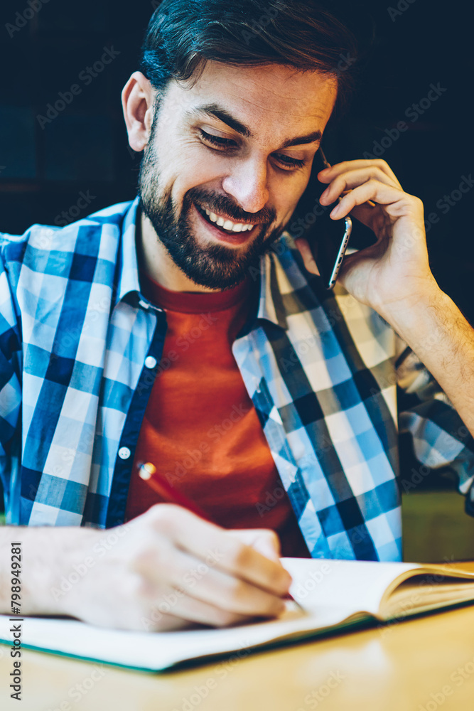 Aufkleber cheerful male hipster blogger communicating with friends during phone conversation on smartphone and