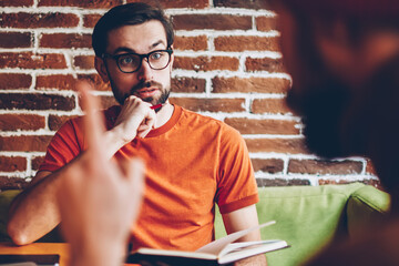 Excited bearded young man in eyeglasses shocked with strategy of developing startup project while...