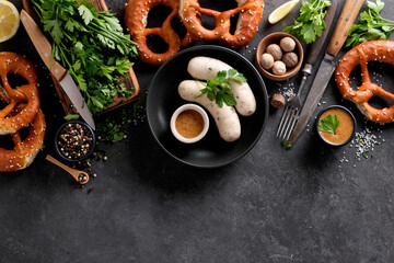 Bavarian white sausages with mustard and pretzel on a black background with copy space.
