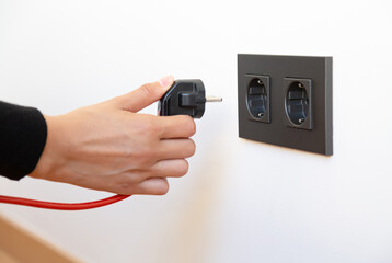 Woman's hand plugging in electrical appliance