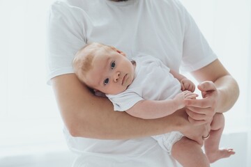 A newborn baby smiling in dad's arms on a white isolated window background, a family with a small...