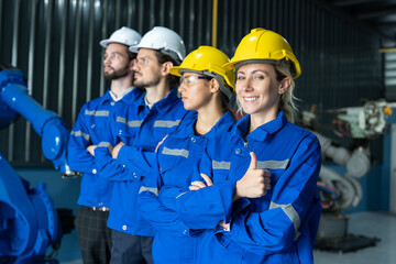 Group of robotic engineers wear helmets safety standing and arms crossed at factory workshop. Technician professional team robot arm welding machine.