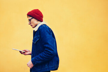 Side view of pensive hipster teen dressed in denim apparel installing application on touch pad...