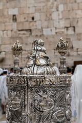 A decorative,  silver crown which sits atop the Sephardic-style case holding the Torah scroll which...