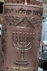 A decorative, Sephardic style Torah in a copper case designed with Jewish symbols, used during prayer services at the Western Wall in Jerusalem.