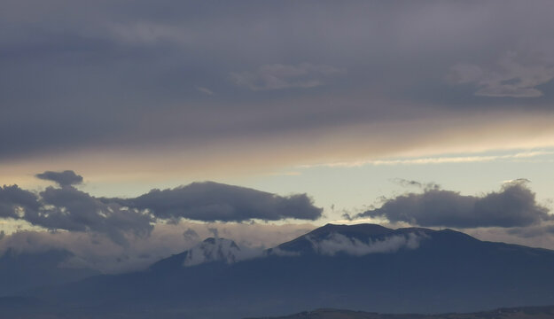 Nuvole bianche e grigie aggrappate come ovatta alle montagne in una giornata invernale al tramonto