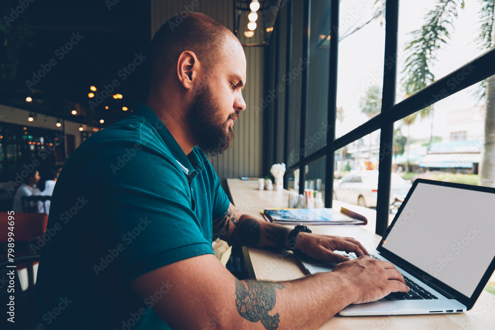 Aufkleber skilled male freelancer using laptop computer with mock up screen and wifi in cafeteria for remote j