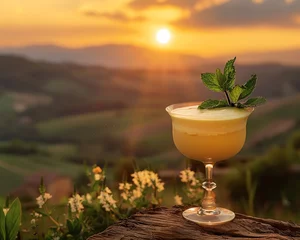 Fotobehang A golden Zabaglione in a vintage glass, garnished with fresh mint, backlit by a warm sunset over a Tuscan landscape © Oranuch