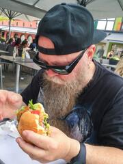 Mann mit langem Bart beißt genüßlich in einen Burger